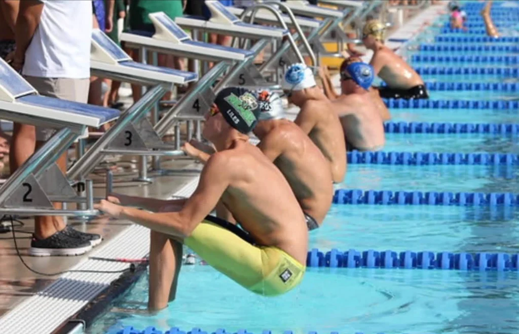 Competitive swimmers preparing to start a race from the pool wall